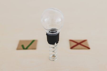 feedback about good and bad ideas conceptual stll-life, lightbulb on spring with green tick and red cross next to itの写真素材