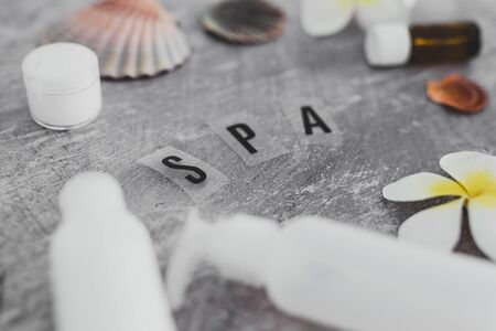 natural beauty products conceptual still-life, lotions and essential oil bottles surrounded by flowers and shells with Spa textの写真素材