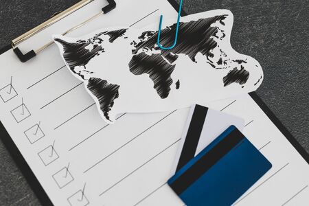 business going global conceptual still-life, world map on clipboard with blank to do list ticked off and with payment cardsの写真素材
