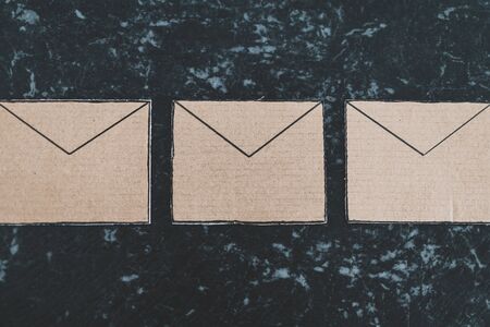 inbox organization conceptual still-life, email envelope icons made of cardboard lined up on a deskの写真素材