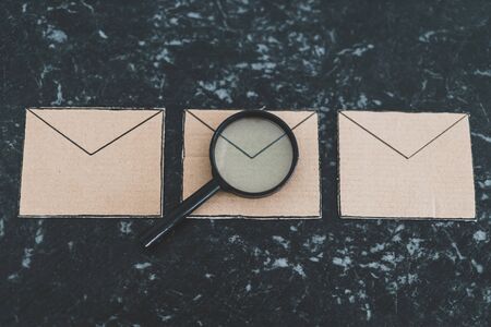 filtering your inbox against spam conceptual still-life, magnifying glass analyzing a specific email envelope out of a groupの写真素材