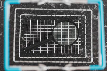 consumerism and market research conceptual still-life, shopping basket with magnifying glass and calculator in itの写真素材