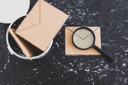filtering or analyzing your inbox for spam conceptual still-life, magnifying glass on email envelope icon next to garbage binの写真素材