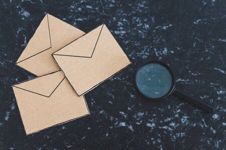 filtering your inbox against spam conceptual still-life, magnifying glass analyzing a specific email envelope out of a groupの写真素材