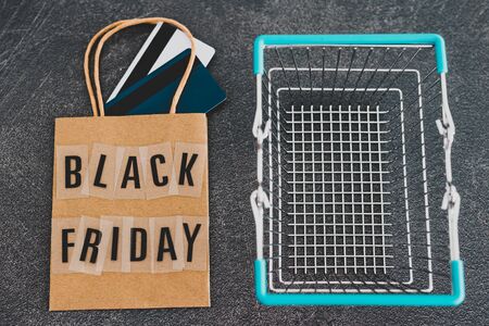 marketing promotional offers and sales conceptual still-life, black Friday shopping bag with payment cards and shopping basket next to itの写真素材