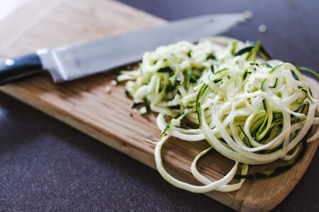 healthy food ingredients, spiralized zucchini noodles with knife on cutting boardの写真素材
