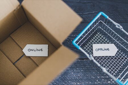online vs retail shopping conceptual still-life, parcel and shopping basket with Online and Offline...