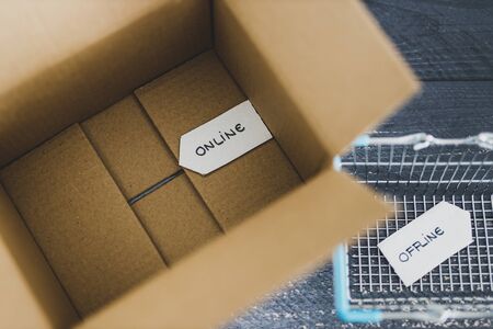 online vs retail shopping conceptual still-life, parcel and shopping basket with Online and Offline...