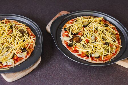 home cooking and meal prepping concept, vegetables pizzas with vegan cheddar topping before going in...