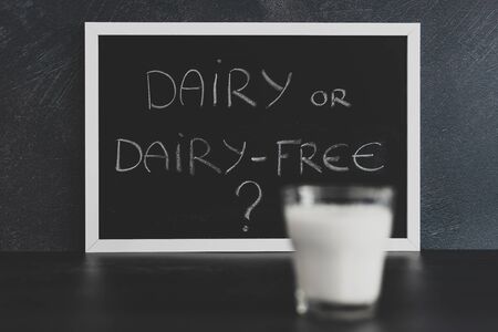 dairy or dairy-free debate about veganism and healthy food, text on blackboard with glass of milk from topdown perspectiveの写真素材