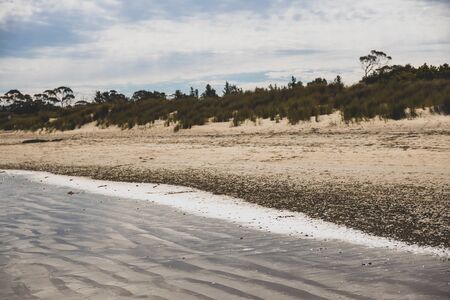Seven Mile Beach in Tasmania, Australia on late spring day with no people and partly cloudy weather