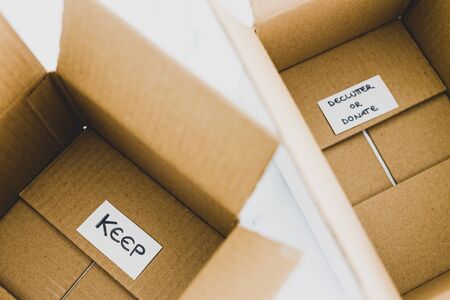 decluttering and tidying up conceptual still-life, white storage boxes to sort between objects to keep and those to declutter or donate with respective labelsの写真素材