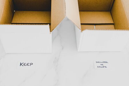 decluttering and tidying up conceptual still-life, white storage boxes to sort between objects to keep and those to declutter or donate with respective labelsの写真素材
