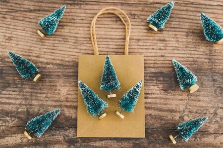 shopping bag with miniature Christmas trees around it ,concept of festive season gift purchases and shoppingの写真素材
