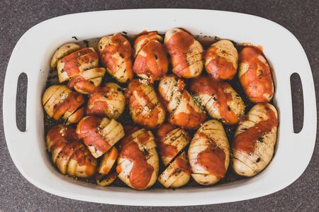 meal prepping healthy plant-based recipes, potato bake with  tomato sauce and herbs about to go in the ovenの写真素材