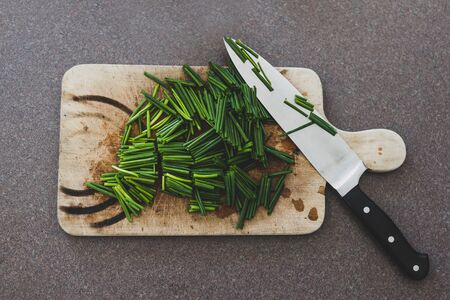meal prepping healthy plant-based recipes, freshly cut chive on chopping board with knife next to itの写真素材