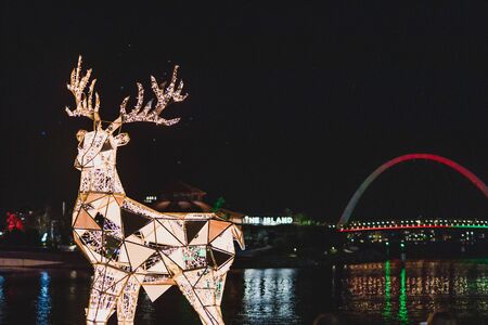 PERTH, WESTERN AUSTRALIA - December 25th, 2019: festive reindeer sculpture and the Elizabeth Quay's pedestrian bridge over the bay and the Swan River by night with Christmas lightsのeditorial素材