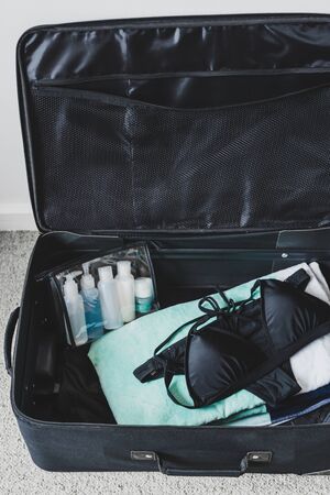 travel essentials and packing light for a holiday concept, luggage with just a  beach towel and...