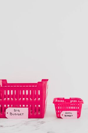 big vs small budget conceptual still-life, different size shopping baskets with text on price tagsの写真素材