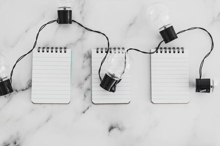 brainstorming and finding innovative ideas for your business conceptual still-life, group of notepads with string of light bulbs on themの写真素材