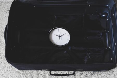 time to travel or delay during a trip conceptual still-life, empty suitcase with clock in it