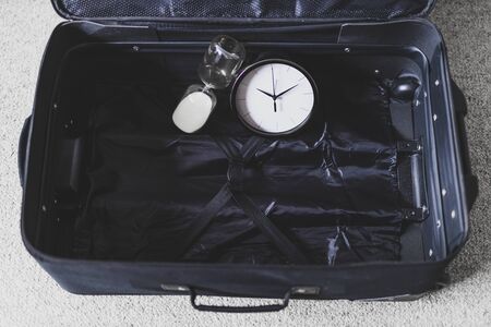 time to travel or delay during a trip conceptual still-life, empty suitcase with clock and hourglass in it の写真素材