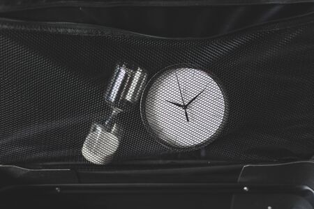 time to travel or delay during a trip conceptual still-life, empty suitcase with clock and hourglass...