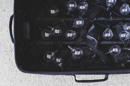 brain drain conceptual still-life, open suitcase with string of lightbulbs symbol of highly trained...