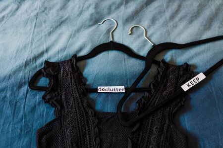 tidying up and decluttering conceptual still-life, clothes hangers with black top and text labels to sort between items to Keep and Declutterの写真素材