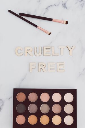 beauty industry and vegan products conceptual still-life, make-up brushes and eyeshadow palette with Cruelty free text next to them referring to the use of synthetic bristle and items not tested on animalsの写真素材