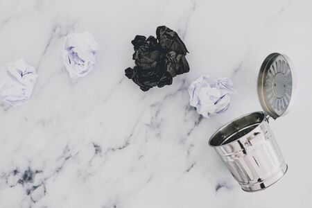 concept of creative block or burnout, group of scrunched paper ball drafts going into garbage bin