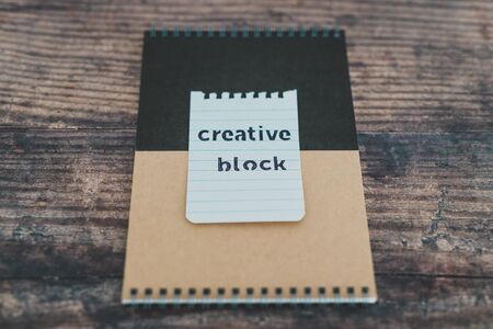 creative block or writer's block conceptual still-life, notepads on wooden desk with text doodle on...