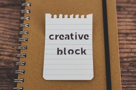 Foto de creative block or writer's block conceptual still-life, notepads on wooden desk with text doodle on piece of paper - Imagen libre de derechos