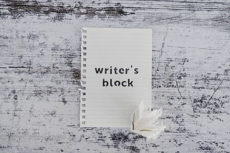 creative block or lack of inspiration conceptual still-life, piece of paper on wooden desk with Writer's Block text with scrunched paper ball next to itの写真素材