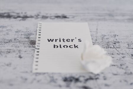creative block or lack of inspiration conceptual still-life, piece of paper on wooden desk with Writer's Block text with scrunched paper ball next to itの写真素材