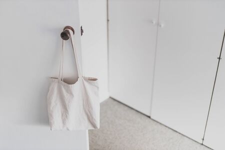 shopping and daily life conceptual still-life, plain white canvas tote bag handging on door knob in front of wardrobe doors with minimalist lookの写真素材