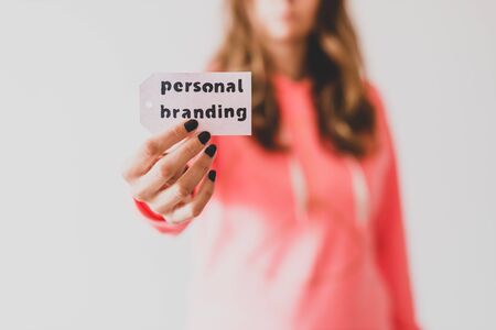 concept of influencers and fame, girl holding Personal Branding message on price tag close to the camera shot at shallow depth of fieldの写真素材