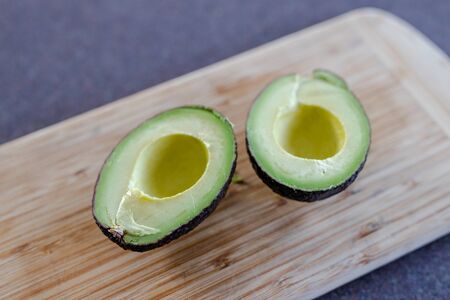 healthy ingredients for a plant-based diet, avocado cut in halves on cutting board