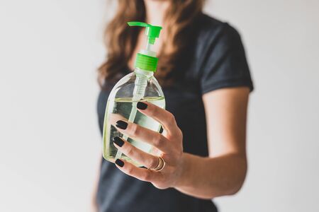 hygiene and protecting from viruses and bacteria, woman holding bottle of hand sanitizer towards the cameraの写真素材