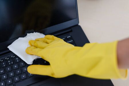 practice good hygiene against viruses and bacteria, hand with cleaning gloves disinfecting laptop keyboard with wipeの写真素材