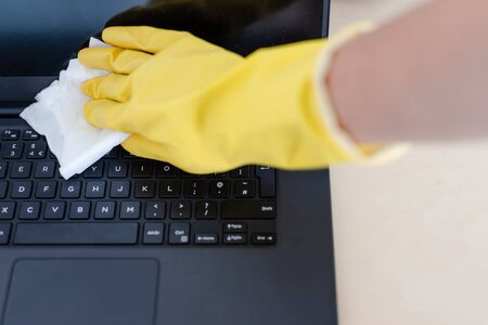 practice good hygiene against viruses and bacteria, hand with cleaning gloves disinfecting laptop...