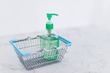 hygiene against viruses and bacteria concept, hand sanitizer bottle inside shopping basket symbol highly sought after products in times of self-isolation and quarantinesの写真素材