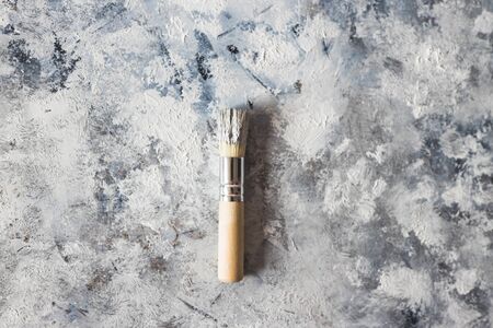 arts and diy concept, brush on top of finished work of an abstract textured painting or photography backdrop on mdf board with paste and neutral toned acrylic paintの写真素材