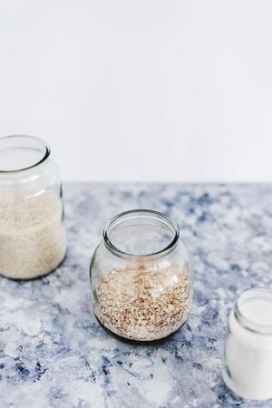 healthy non-perishable food ingredients for vegan pantry, glass jars with oats flour and rice の写真素材
