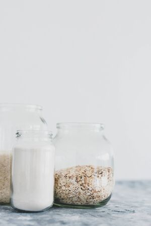 healthy non-perishable food ingredients for vegan pantry, glass jars with oats flour and rice の写真素材