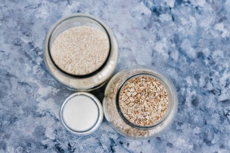 healthy non-perishable food ingredients for vegan pantry, glass jars with oats flour and riceの写真素材