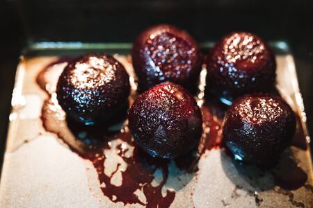 healthy food ingredients and organic produce concept, whole beetroot roasted in the oven on oven tray with juice spilling outの写真素材