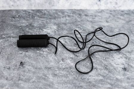 fitness and home gym gear concept, skipping rope for intense cardio workouts on concrete background
