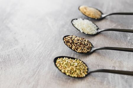 food ingredients for a healthy plant-based diet, spoons lined up on kitchen counter with mixed...