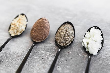 food ingredients for a healthy plant-based diet,  spoons lined up on kitchen counter with sweet ingredients including coconut cocoa oats and chia seedsの写真素材